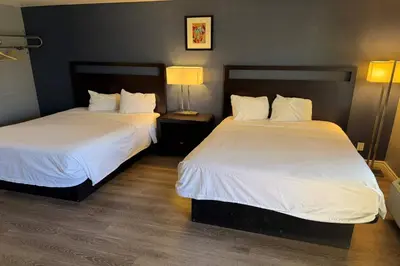 two beds in a hotel room with white sheets at Travelodge by Wyndham Hemet CA in Hemet