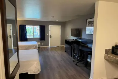a hotel room with a bedroom with a desk and a bed at Travelodge by Wyndham Hemet CA in Hemet