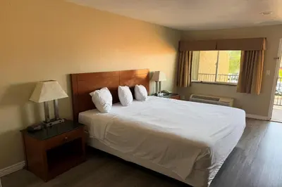 a bedroom with a large bed with white sheets and pillows at Travelodge by Wyndham Hemet CA in Hemet