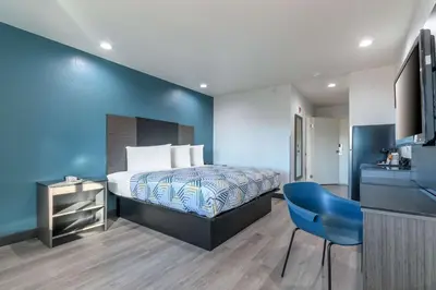 a bedroom with a bed and a blue wall at Studio 6 Suites Perris, CA in Perris