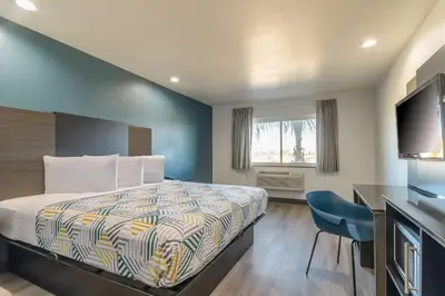 a bedroom with a bed and a desk and a television at Studio 6 Suites Perris, CA in Perris