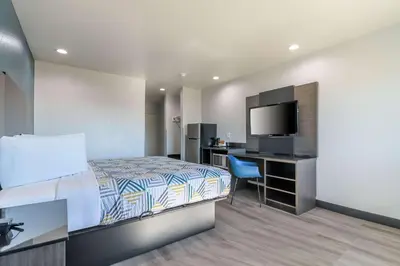 a bedroom with a bed and a desk with a television at Studio 6 Suites Perris, CA in Perris