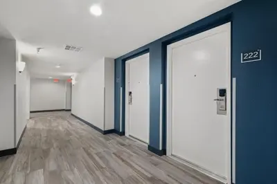an empty hallway with white doors and wood floors at Studio 6 Suites Perris, CA in Perris
