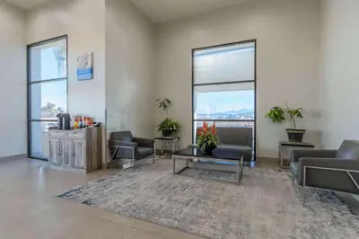 a waiting room with couches and tables and windows at Studio 6 Suites Perris, CA in Perris