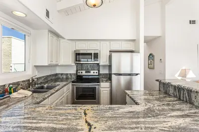 a kitchen with white cabinets and stainless steel appliances at 2BR Oceanfront Condo - Private Balcony - Spacious in Oceanside