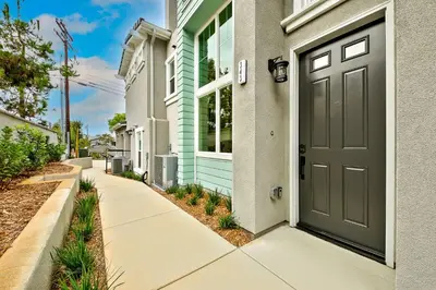a house with a green door and a sidewalk at Modern 4BR - Private Balcony - Garage Parking in Carlsbad