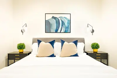 a bedroom with a white bed with blue pillows at Modern 4BR - Private Balcony - Garage Parking in Carlsbad