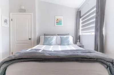 a white bedroom with a large bed with blue pillows at Not taking reservations in Chula Vista