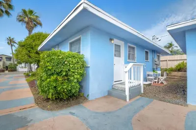 a blue house with a bush in front of it at Walk To Beach - EV Charger - Outdoor Dining - 2BR in Carlsbad