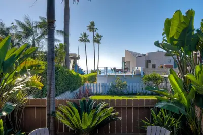 a garden with palm trees and a house at Walk To Beach - BBQ - Fire Pit - Outdoor Dining in Carlsbad