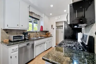 a kitchen with white cabinets and a stove top oven at Walk To Beach - BBQ - Fire Pit - Outdoor Dining in Carlsbad