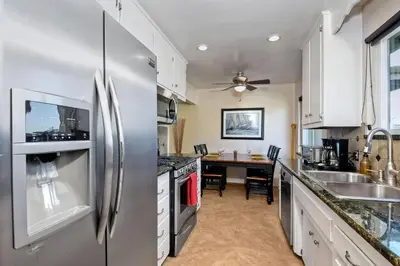 a kitchen with a stainless steel refrigerator and a table at Walk To Beach - BBQ - Fire Pit - Outdoor Dining in Carlsbad