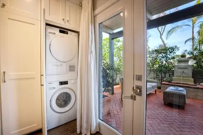 a laundry room with a washer and dryer next to a door at 90 Walk Score, Steps to Beach, Dining in Carlsbad