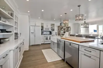a kitchen with white cabinets and a large island at Luxury Ocean Views - 6 BR Home - Steps to Sand in Carlsbad