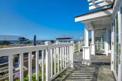 a white house with a white fence next to the beach at Luxury Ocean Views - 6 BR Home - Steps to Sand in Carlsbad