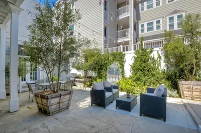 a patio with furniture and trees in front of a building at Juniper Beach Entire Home - Sleeps 18 - Oceanfront in Carlsbad
