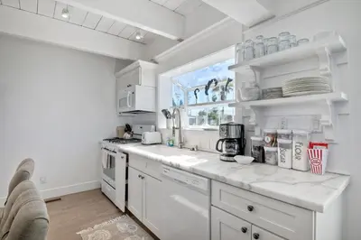 a white kitchen with white appliances and a window at Juniper Beach Entire Home - Sleeps 18 - Oceanfront in Carlsbad