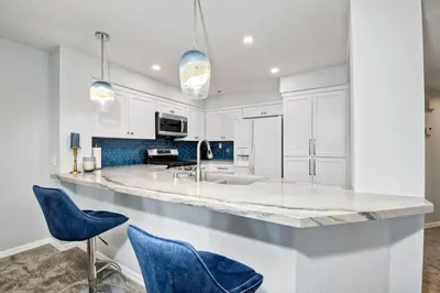 a kitchen with white cabinets and blue chairs at Ocean View, Pool, Hot Tub, Steps To Pier, Gated in Oceanside