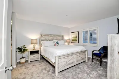 a white bedroom with a bed and a chair at Ocean View, Pool, Hot Tub, Steps To Pier, Gated in Oceanside