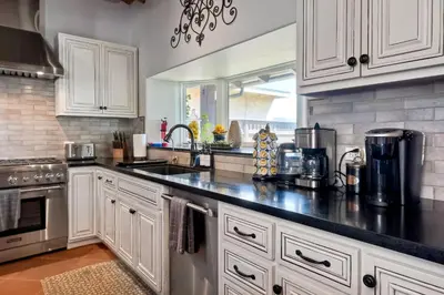a kitchen with white cabinets and a black counter top at Walk To The Beach - Outdoor Dining - Spacious in Carlsbad