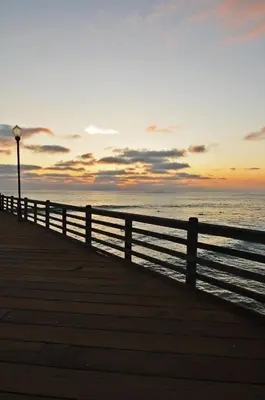 a wooden pier with a fence and the ocean at sunset at Aquamarine Villas in Oceanside