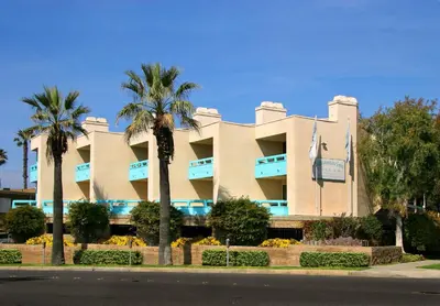 a building with palm trees in front of it at Aquamarine Villas in Oceanside