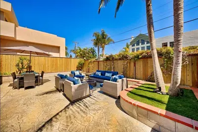 a patio with couches and tables and palm trees at Windansea Coastal Haven - Steps to Beach in San Diego