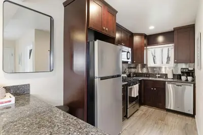 a kitchen with a white refrigerator and wooden cabinets at Windansea Coastal Haven - Steps to Beach in San Diego