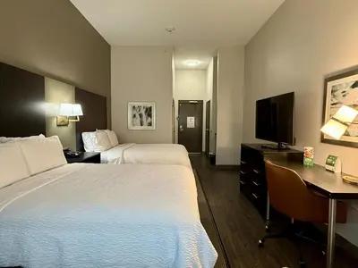 a hotel room with two beds and a desk and a television at Holiday Inn Carlsbad/San Diego by IHG in Carlsbad