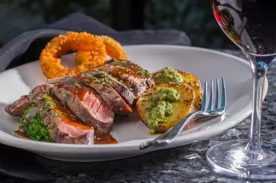 a plate of steak and onion rings and a glass of wine at Holiday Inn Carlsbad/San Diego by IHG in Carlsbad