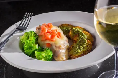 a plate of food with broccoli and vegetables and a glass of wine at Holiday Inn Carlsbad/San Diego by IHG in Carlsbad