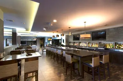 a restaurant with a bar with wooden tables and chairs at Holiday Inn Carlsbad/San Diego by IHG in Carlsbad