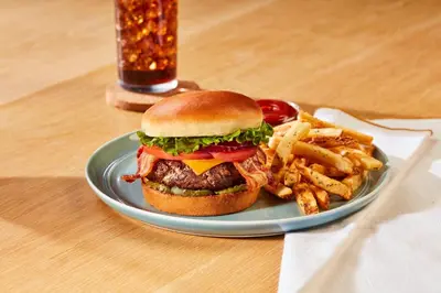 a plate with a hamburger and french fries on a table at Holiday Inn Carlsbad/San Diego by IHG in Carlsbad