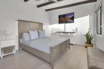 a bedroom with a large bed and a tv on the wall at New! Luxury 5BR, W/Arcade, Sauna, Views, Fire Pit! in San Diego