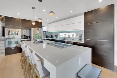 a kitchen with a large white island with chairs at New! Luxury 5BR, W/Arcade, Sauna, Views, Fire Pit! in San Diego