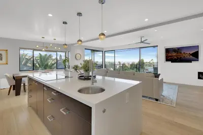 a kitchen with a sink and a living room at New! Luxury 5BR, W/Arcade, Sauna, Views, Fire Pit! in San Diego