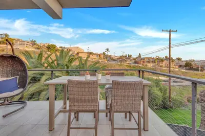 a patio with a table and chairs on a balcony at New! Luxury 5BR, W/Arcade, Sauna, Views, Fire Pit! in San Diego