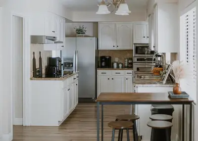 a kitchen with white cabinets and a table and stools at San Diego Trail Guest Ranch in Poway