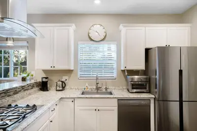 a kitchen with white cabinets and a clock on the wall at Wonderland Retreat - Near Downtown, Free Parking in San Diego