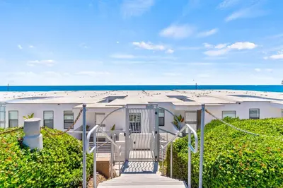 a white building with stairs leading to the beach at Oceanside Oasis 700S-103 in Oceanside