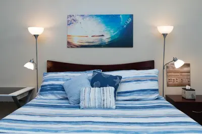 a bed with blue and white striped sheets and two lamps at * - The Leucadia Beach Grotto - * An Encinitas Gem in Encinitas