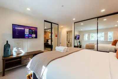 a bedroom with a large white bed and a tv at Sur La Mer, beachfront, tidal pools in San Diego