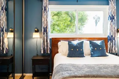 a bedroom with a bed with blue walls and a window at Sur La Mer, beachfront, tidal pools in San Diego