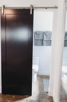 a black door in a bathroom with a toilet at Casa de Vaqueros! Family&Pet Friendly! 3mi to the Beach! in San Juan Capistrano
