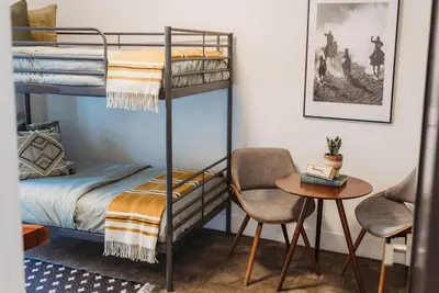 a bedroom with bunk beds with a table and a chair at Casa de Vaqueros! Family&Pet Friendly! 3mi to the Beach! in San Juan Capistrano
