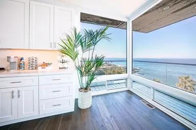 a kitchen with white cabinets and a large window at Panoramic Ocean Vistas With Hot Tub and Firepit in San Diego