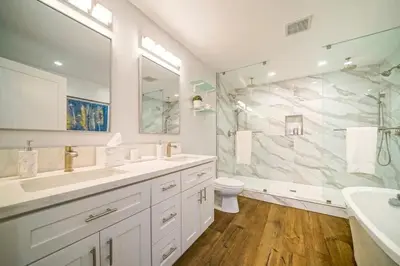 a white bathroom with two sinks and a shower at Panoramic Ocean Vistas With Hot Tub and Firepit in San Diego