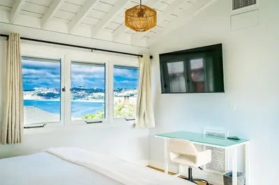 a bedroom with a bed and a desk and windows at Blue Water View Condo in Prime Coastal Locale in San Diego