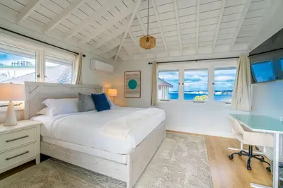 a bedroom with a bed and a desk and windows at Blue Water View Condo in Prime Coastal Locale in San Diego