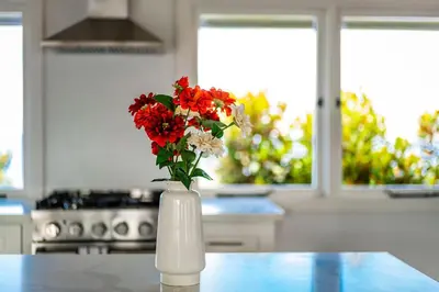 a white vase with red and white flowers on a counter at Blue Water View Condo in Prime Coastal Locale in San Diego
